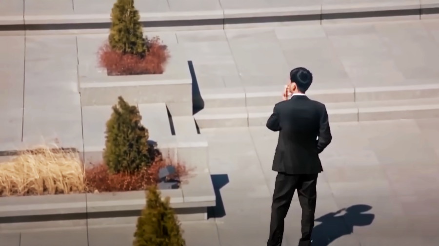 A long shot of a man discontented back facing the camera smoking a cigarette in contemplation