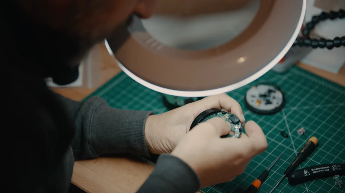 An image of Julian Bleecker at the workbench assembling an OMATA One cycling computer he designed and built in 2014